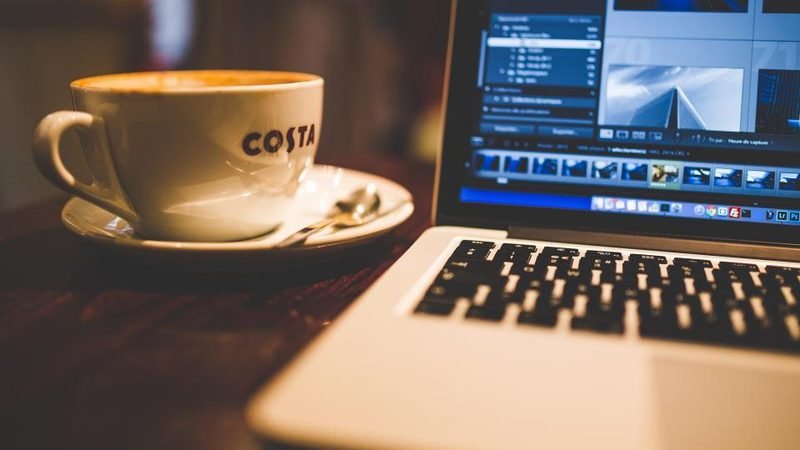 Laptop on a desk running slowly beside a cup of coffee