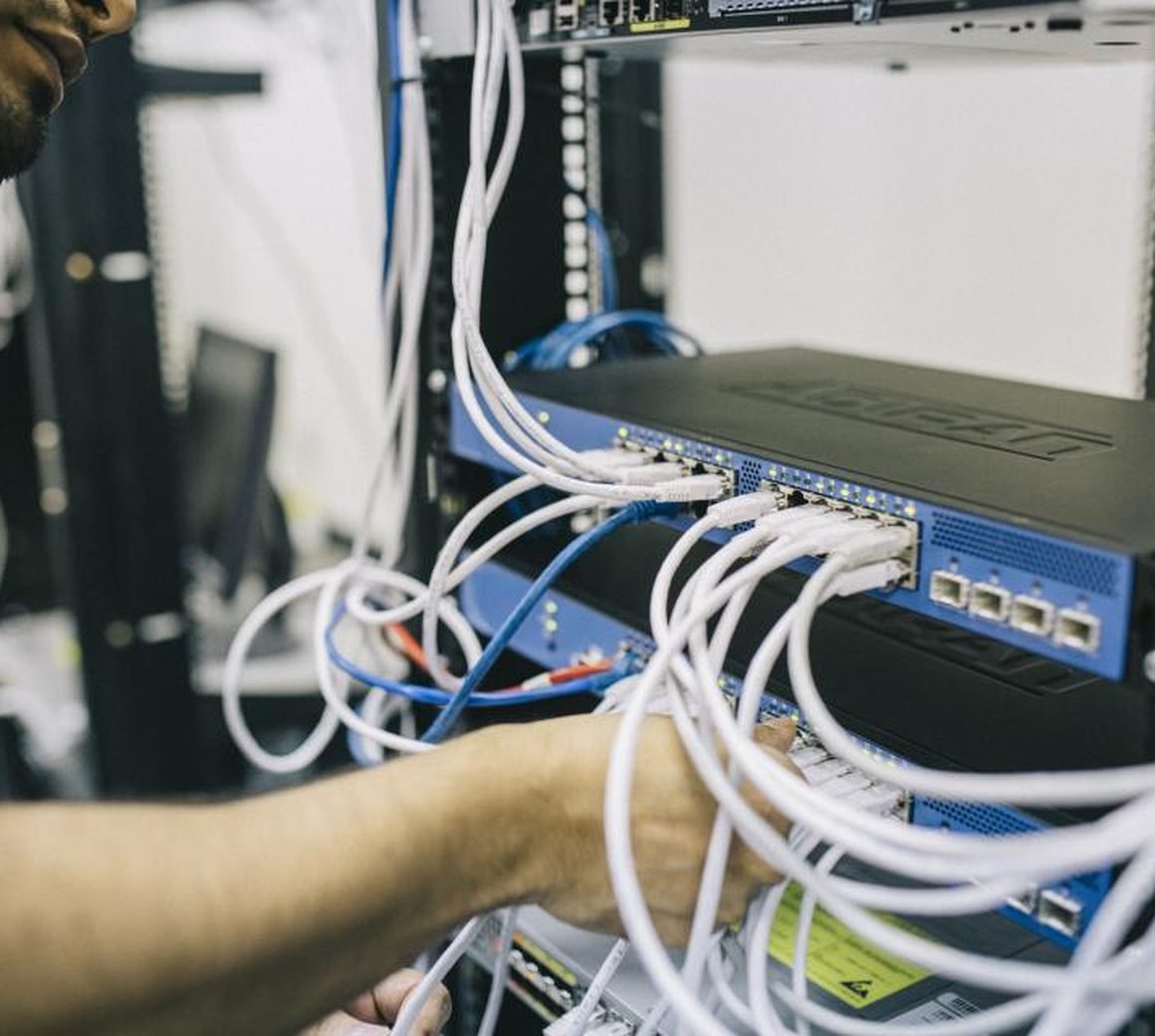 Technician terminating network cables inside a patch panel and switch rack